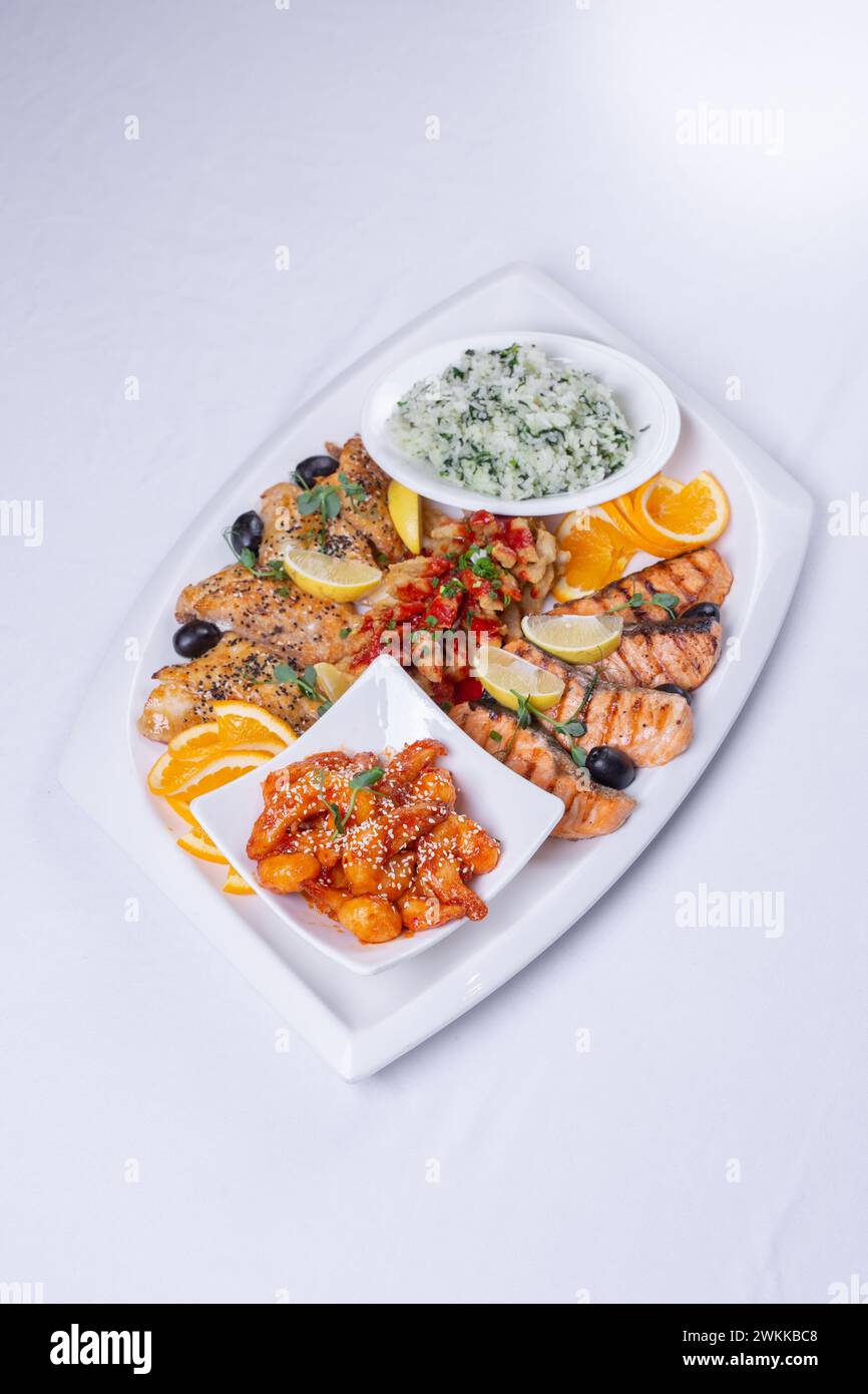 Mischung aus Meeresfrüchten. Köstlicher gegrillter Fisch, Garnelen in Sauce und Lachs auf der Tischplatte. Stockfoto