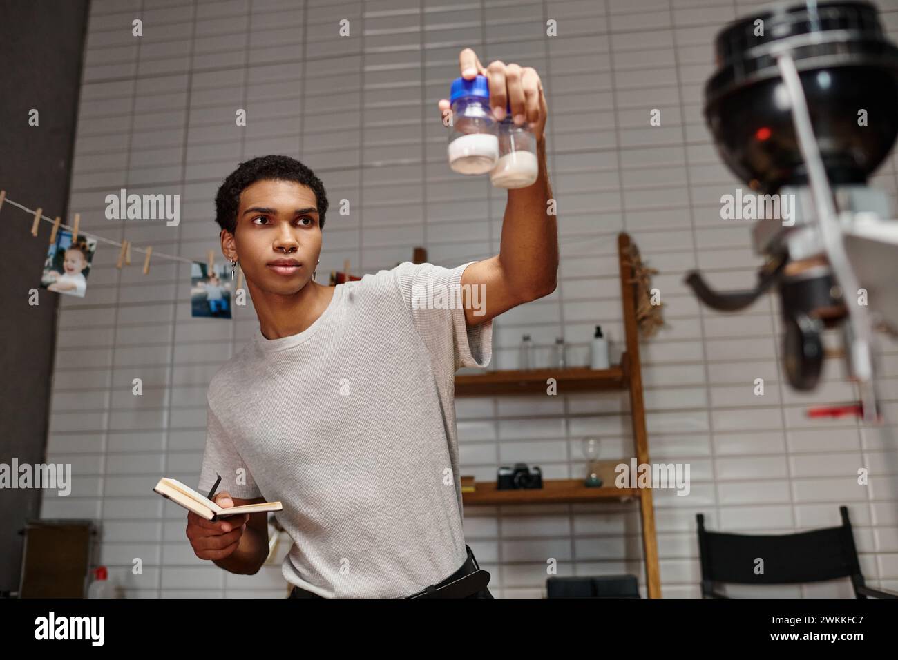 Schöner afroamerikanischer Fotograf, der Flaschen mit Folienentwicklungspulver und Notizbuch hält Stockfoto