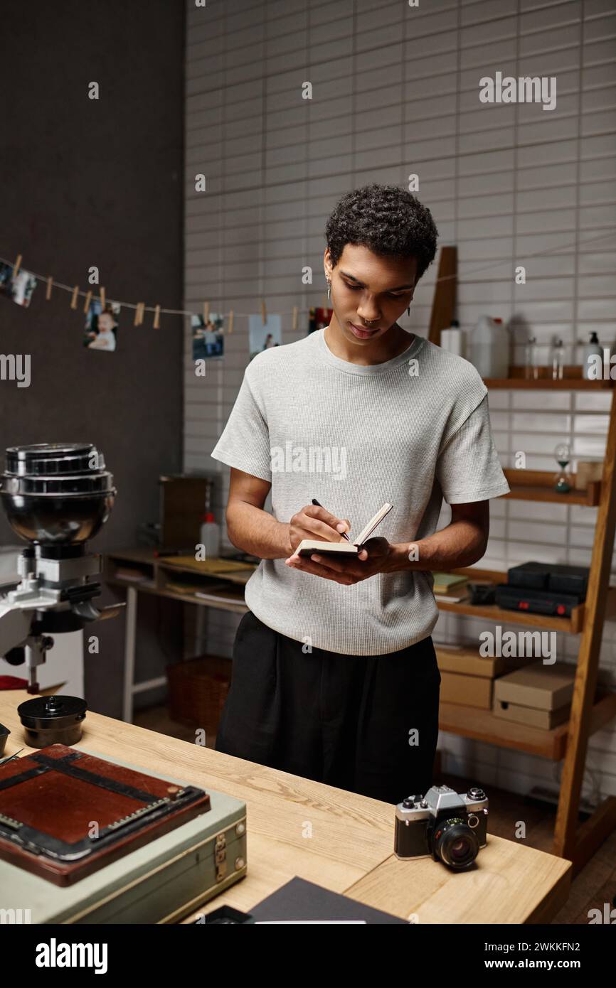 Der junge afroamerikaner tauchte in die Schrift ein und stand in der Nähe einer analogen Kamera im Fotostudio Stockfoto