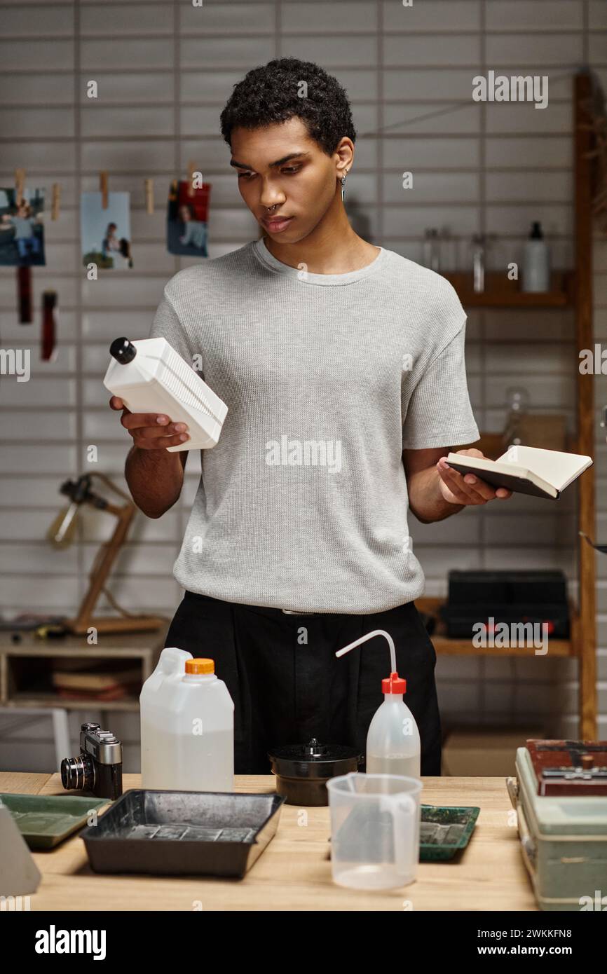 Junger afroamerikanischer Fotograf, der chemische Lösung mit Notebook hält, Filmentwicklung Stockfoto