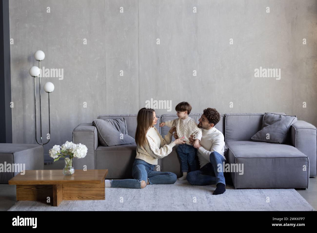 Porträt von aufgeregten Eltern mit süßem kleinen Sohn, der in einer neuen Wohnung posiert. Stockfoto