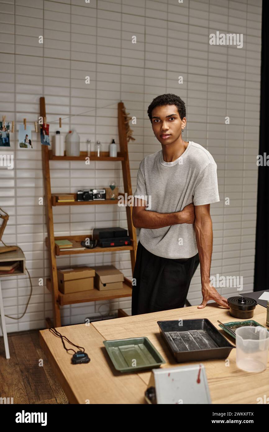 Junger afroamerikanischer Fotograf, der in einem Fotolabor mit hängenden Filmfotos steht Stockfoto