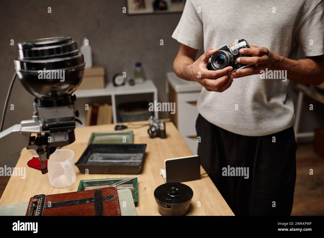 Beschnittener schwarzer Mann, der eine analoge Kamera hält, während er in einem Fotolabor steht, Filmfotografie Stockfoto