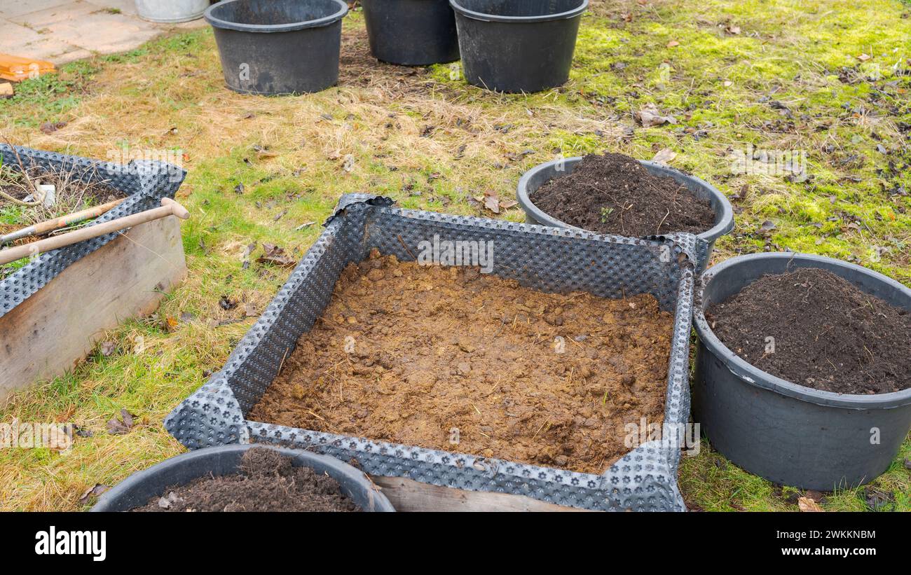 Hochbeet im Garten, gefllt mit Pferdemist als Dnger mit Eimern von Erde  um ihn herum Stockfotografie - Alamy