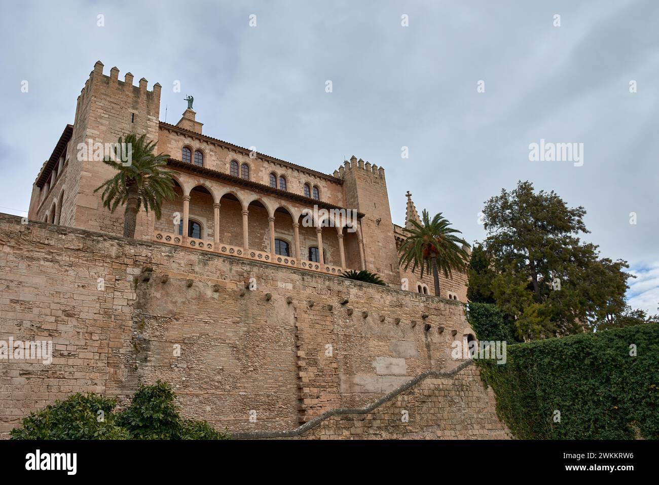 Blick von unten auf den Königlichen Palast von La Almudaina mit einigen Bäumen in Palma de Mallorca, Balearen, Spanien Stockfoto