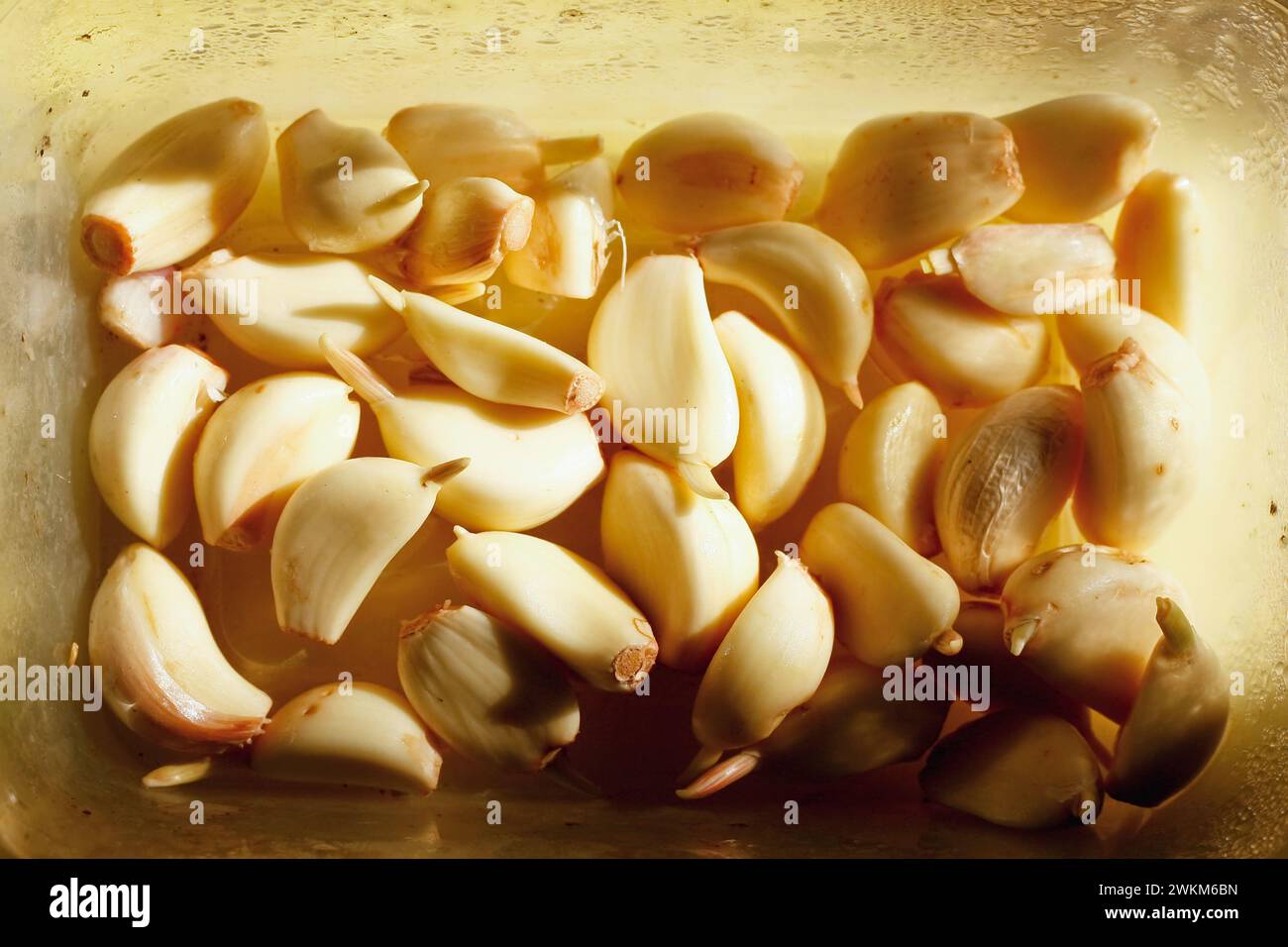 Schließen Sie einen Haufen geschälter Knoblauchzehen auf einer schmutzigen Plastikkiste Stockfoto