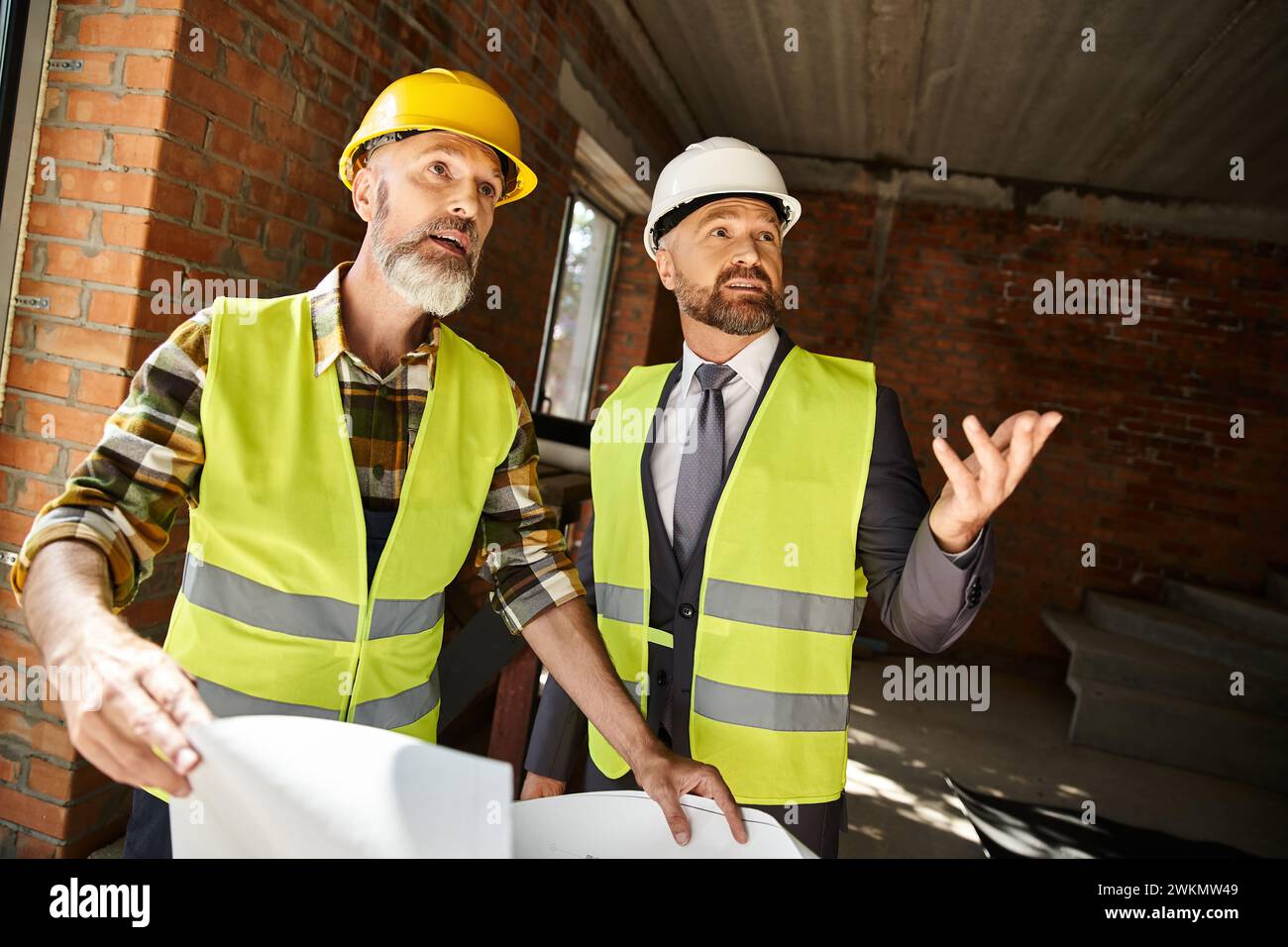 Jolly Cottage Builder und Geschäftsmann mit Blueprint über ihre Arbeit auf der Baustelle Stockfoto