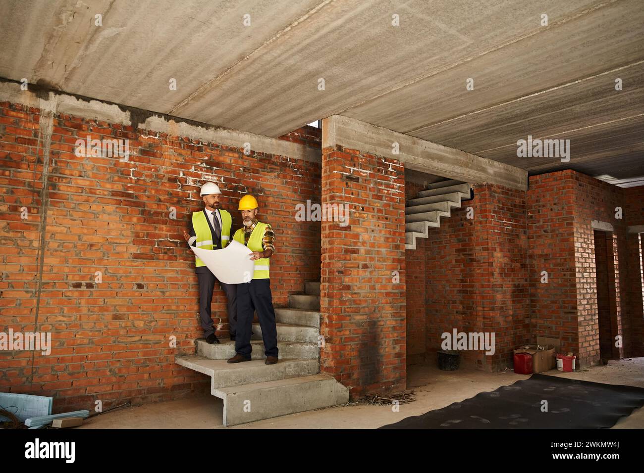 Attraktiver bärtiger Hüttenbauer und Architekt, der auf der Baustelle mit Bauplan arbeitet Stockfoto