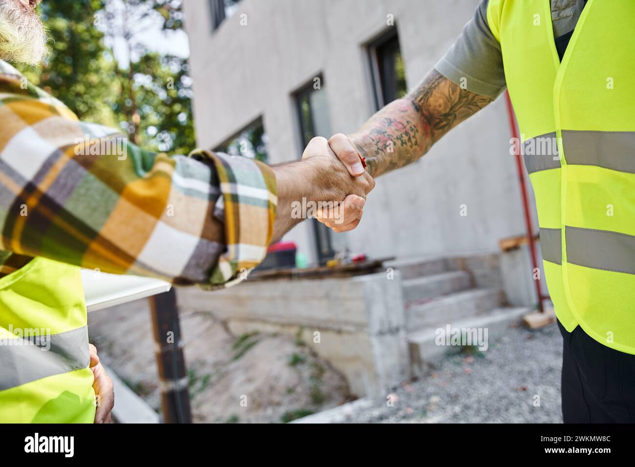 Zugeschnittene Ansicht von zwei hart arbeitenden Bauarbeitern, die sich die Hände schütteln, Hüttenbauern Stockfoto