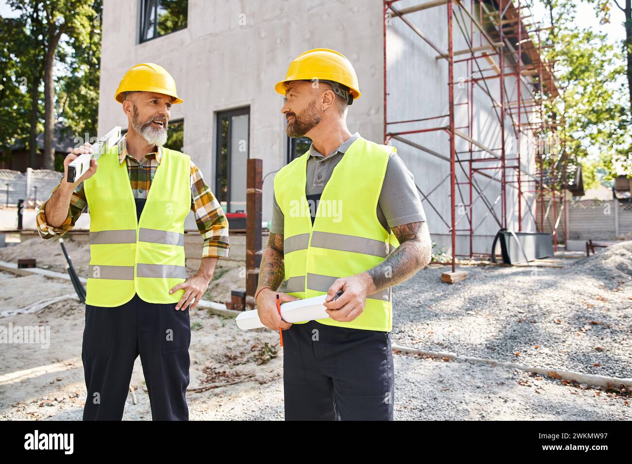 Attraktive Bauarbeiter, die sich gegenseitig anschauen, Bauherren Stockfoto