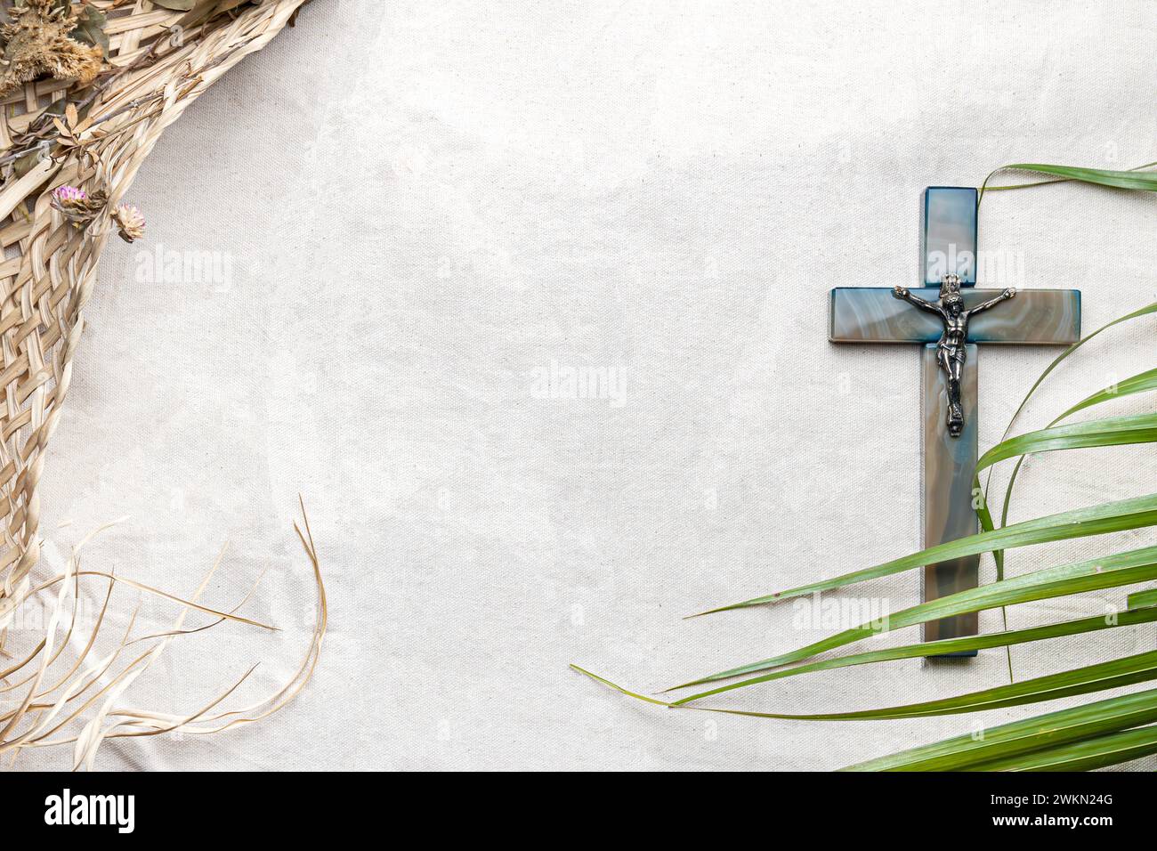 Blick von oben auf einen Hintergrund der heiligen Woche mit einem Kruzifix und Palmen auf einem weißen Stoff Stockfoto