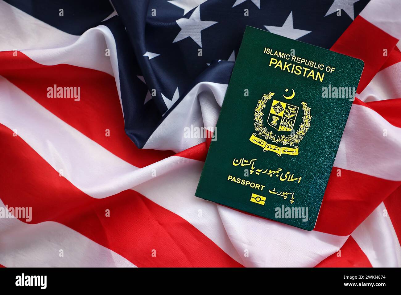 Grüner Pass der Islamischen Republik Pakistan auf dem Hintergrund der US-Nationalflagge Nahaufnahme. Tourismus und Diplomatie Stockfoto