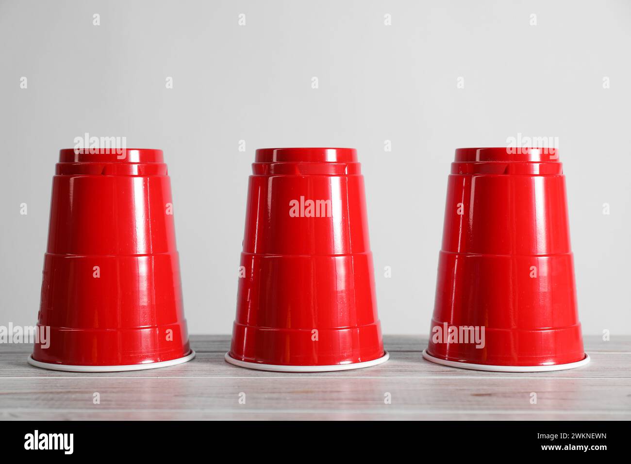 Shell-Spiel. Drei rote Tassen auf Holztisch Stockfoto