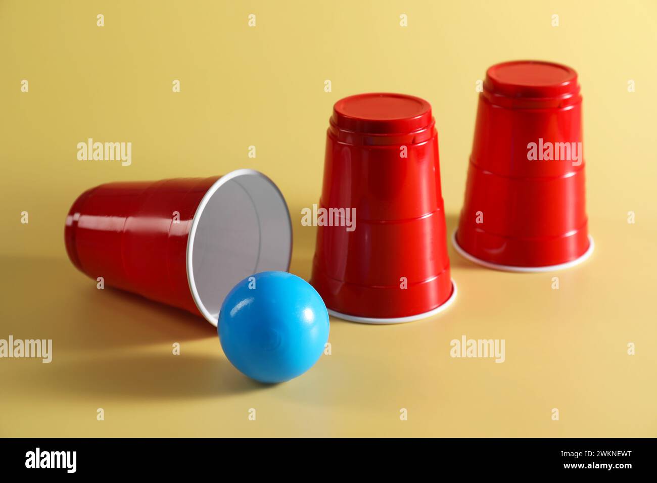 Shell-Spiel. Drei rote Becher und Ball auf gelbem Hintergrund Stockfoto