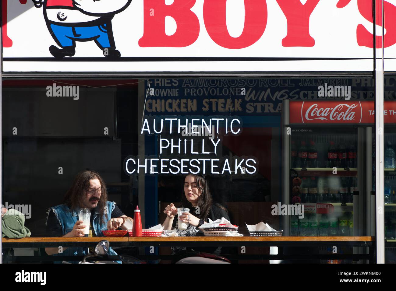 Zwei Personen essen und trinken in einem Café, das authentische Philly Cheesesteaks und anderes Fast Food bietet, in Melbourne City, Australien. Stockfoto
