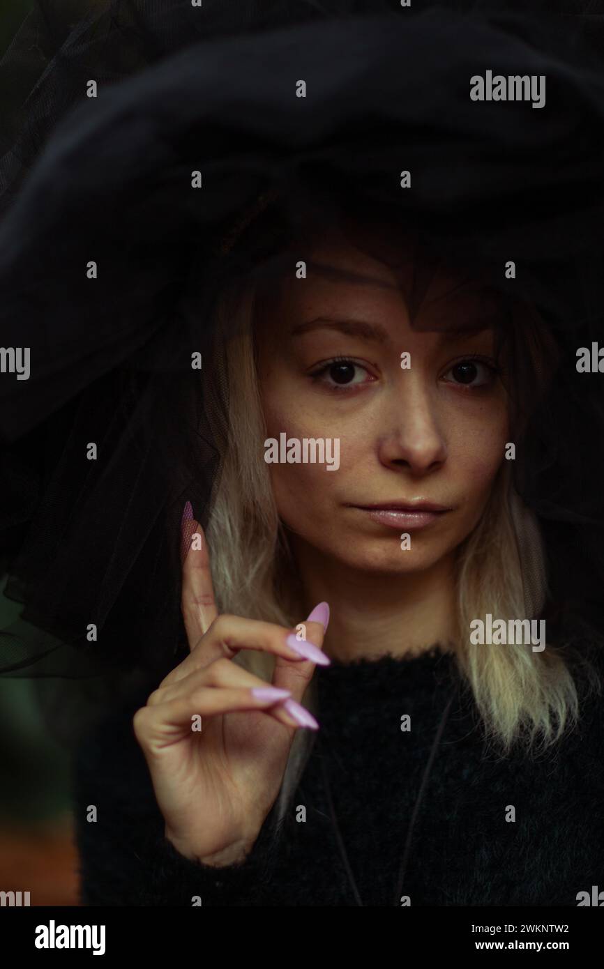 Moody Porträt einer Frau mit kontemplativem Ausdruck, die eine Handgeste macht Stockfoto