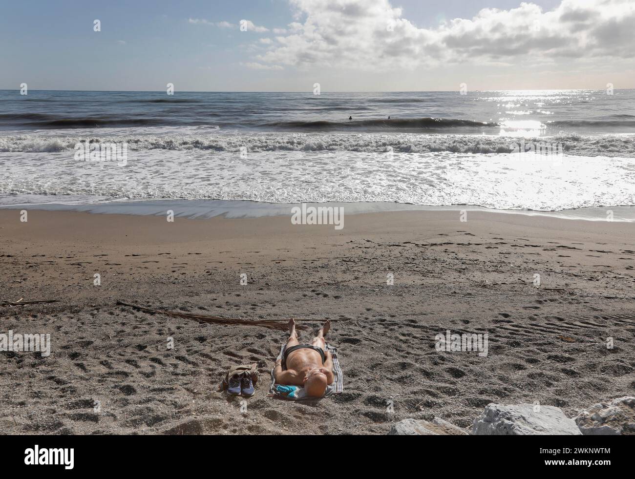 Ein Mann sonnt sich am einsamen Strand von Torremolinos, Spanien, Costa del Sol, 13/02/2019 Stockfoto