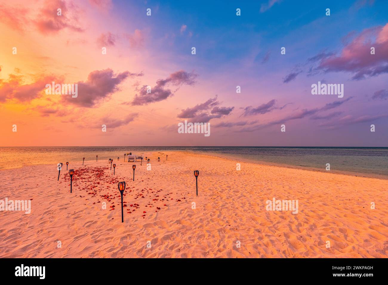 Fantastisches romantisches Jubiläumsangebot zum Abendessen am Strand auf Sandkerzen unter Sonnenuntergang. Romantische Liebe, luxuriöses Abendessen, exotische Tischgestaltung Stockfoto