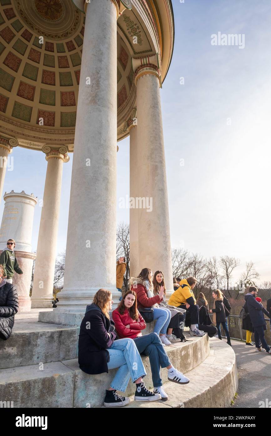 Junge Frau, die die Sonne an einem warmen Tag Ende Februar im Monopteros im Englischen Garten in München genießt Stockfoto