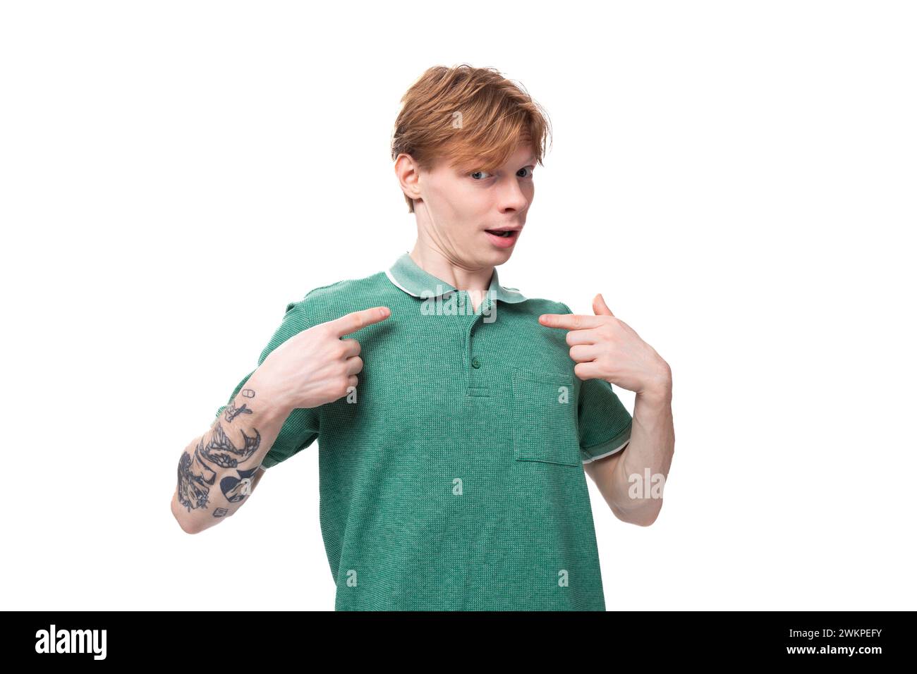 Junger emotionaler kaukasischer Mann mit rotem Haar in einem grünen T-Shirt zeigt seine Coolness vor dem Hintergrund mit Kopierraum Stockfoto
