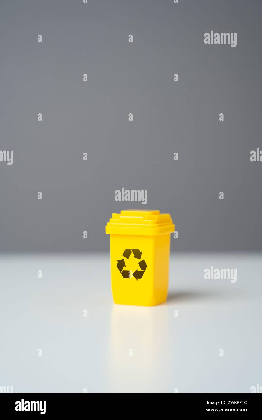 Gelber Recyclingbehälter auf grauem Hintergrund. Verkauf von recyceltem Material oder Erhalt von Zuschüssen für umweltfreundliche Projekte. Kreislaufwirtschaft. Erhaltung der natürlichen Ressourcen, Stockfoto