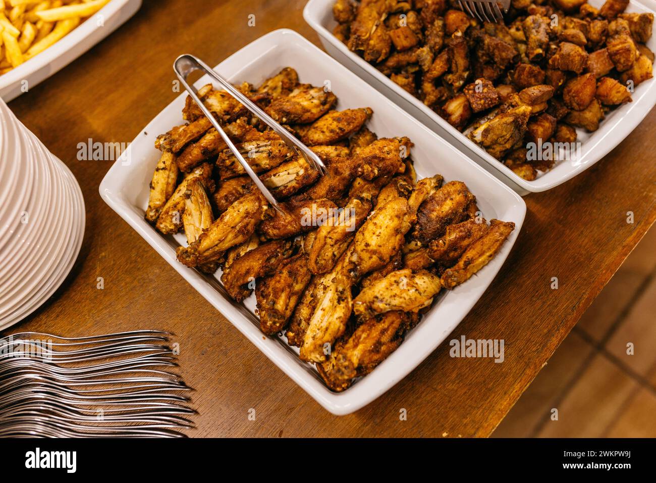 Ein hölzerner Tisch mit weißen Tellern und einer Auswahl an leckeren Speisen Stockfoto