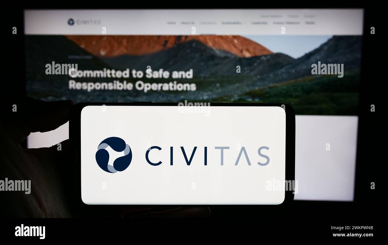 Person, die ein Mobiltelefon mit dem Logo des US-amerikanischen Öl- und Gasunternehmens Civitas Resources Inc. Vor der Webseite des Unternehmens hält. Schwerpunkt auf dem Display des Telefons. Stockfoto