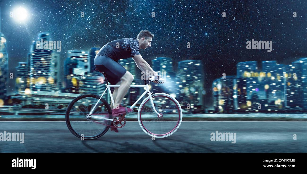 Mann, der nachts vor einer Skyline der Stadt Fahrrad fährt Stockfoto