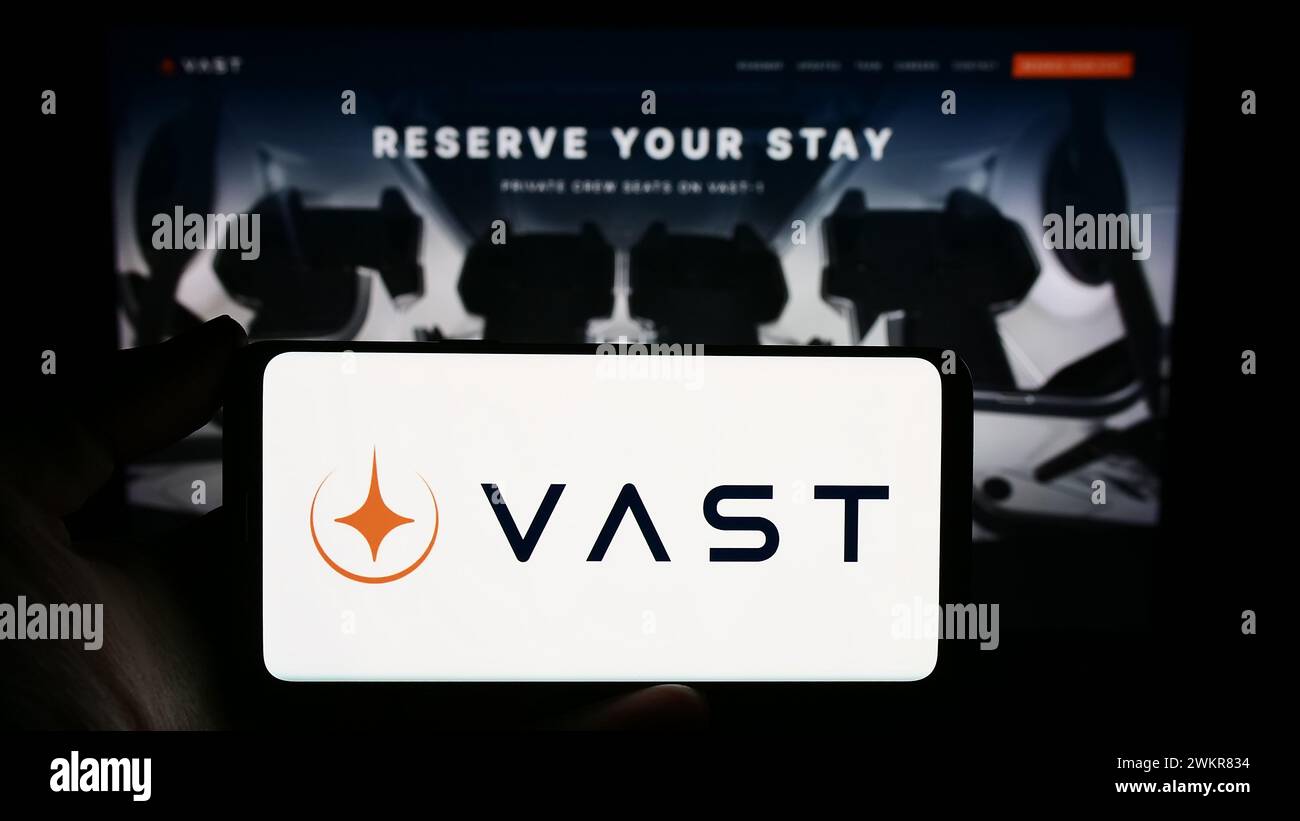 Person mit Smartphone und Logo des US-Luftfahrtunternehmens VAST Space LLC vor der Website. Schwerpunkt auf dem Display des Telefons. Stockfoto