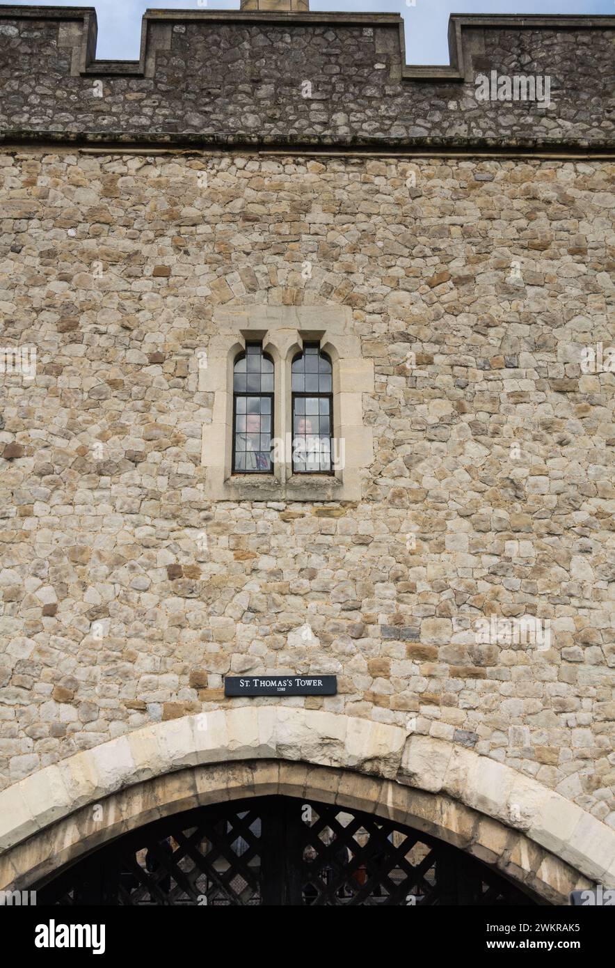 Touristen, die durch die bleihaltigen Fenster über dem Verräter' Gate im Tower of London, England, Großbritannien schauen Stockfoto