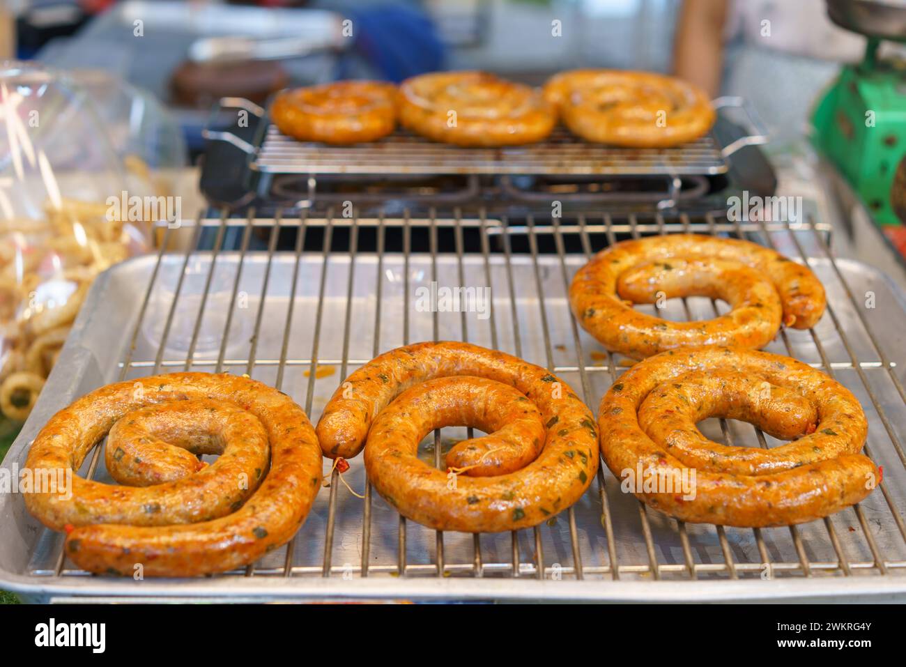 Eine verlockende Präsentation von Sai Oua, der traditionellen nordischen thailändischen Wurst, die perfekt gegrillt und auf einem Metallregal präsentiert wird. Diese Würstchen sind bekannt für Stockfoto