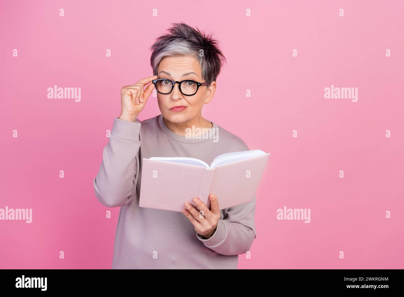 Foto von gesinnter intelligenter Seniorin tragen trendige Kleidung halten Buch Lehrbuch isoliert auf rosafarbenem Hintergrund Stockfoto