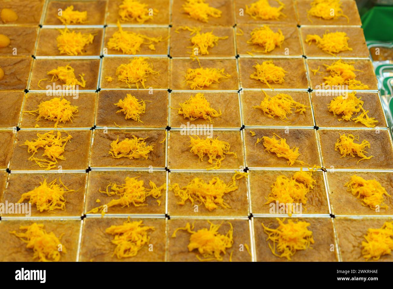 Einheitlich angeordnetes thailändisches Dessert, Mo Kaeng, mit kleinen goldenen Kugeln aus Eigelb und Zucker, auf quadratischem Schliff gesetzt, das den traditionellen AR repräsentiert Stockfoto