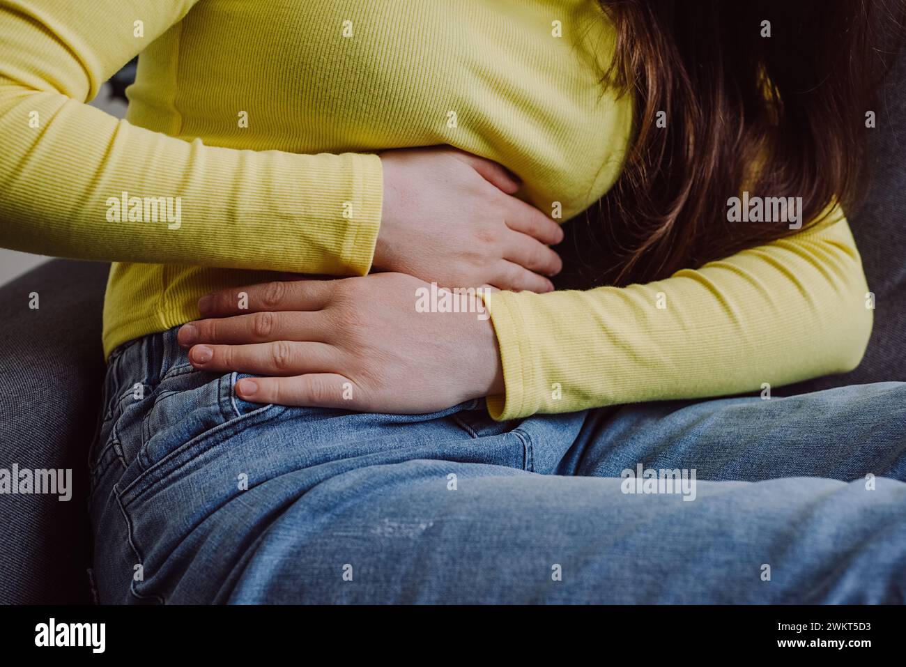 Nahaufnahme einer unbekannten jungen Frau mit Menstruationsschmerzen. Mädchen mit Händen, die den Bauch zusammendrücken und schmerzhafte Bauchschmerzen oder Periodenkrämpfe haben Stockfoto