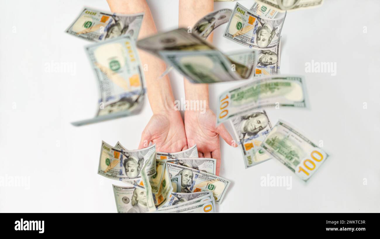 Fliegende Dollars fallen auf die Hände von Frauen. Unscharfer Fokus. Das Konzept von Wohlstand, Erfolg, Sponsoring. Stockfoto