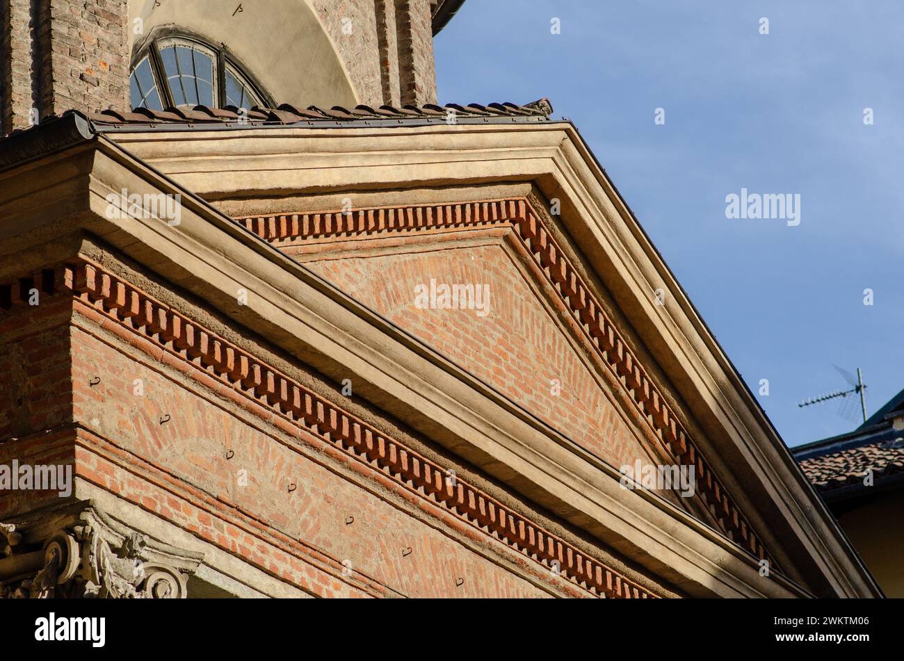 Besondere Architektur, Giebelfassade eines neoklassizistischen Gebäudes mit unverputztem Backstein, mit Gesimsen, Regalen und Dekorationen. Historische Fassade Stockfoto