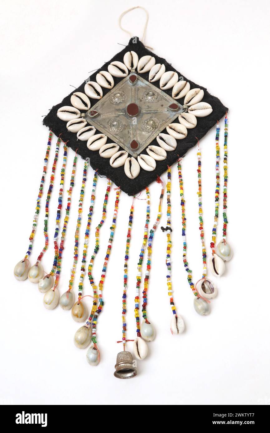 Wandbehang mit einem Kreuz auf Metallplatte mit Karneol-Steinen und hängenden Perlen mit Cowrie-Muscheln am Ende Stockfoto
