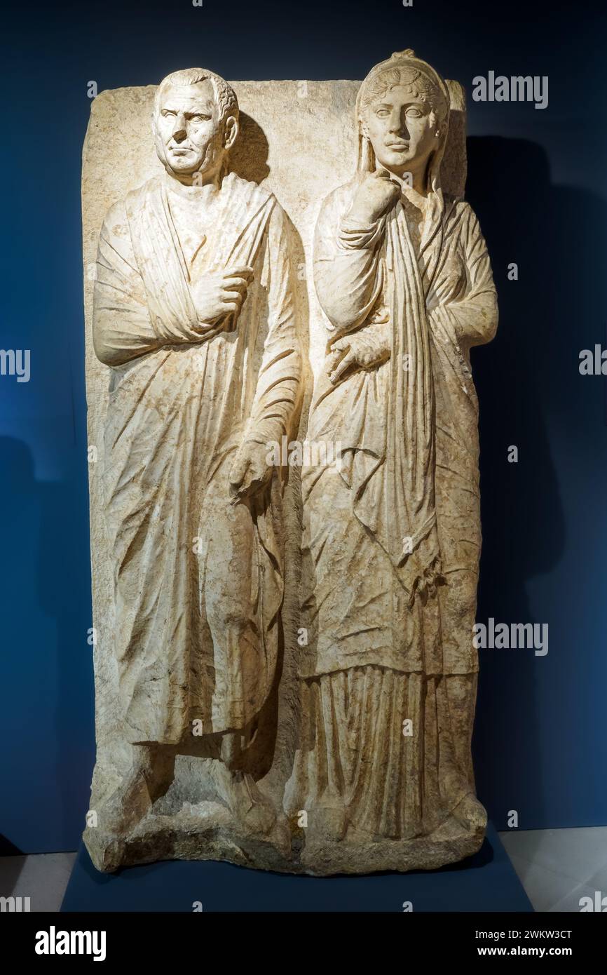 Bestattungshilfe mit zwei Ehegatten - ca. 50 v. Chr., Kalkstein - diese Stele gehört zu einer großen Klasse von Grabreliefen, die zwischen dem ersten Jahrhundert v. Chr. und dem ersten Jahrhundert n. Chr. für Kunden aus dem aufstrebenden Mittelstand, die von ehemaligen Freigelassenen abstammen, hergestellt wurden. Es handelt sich dabei um ein früher versklavtes, wohlhabendes Ehepaar, das stolz seinen Status der freien Staatsbürgerschaft durch die Sprache der Bilder betonen wollte. Der Ehemann wird in seine Toga eingewickelt, die Garderobe, die die römische Staatsbürgerschaft synbolisiert, während seine Frau, die deutlich jünger als ihr Ehemann ist, sich für eine Darstellung gemäß t entschieden hat Stockfoto