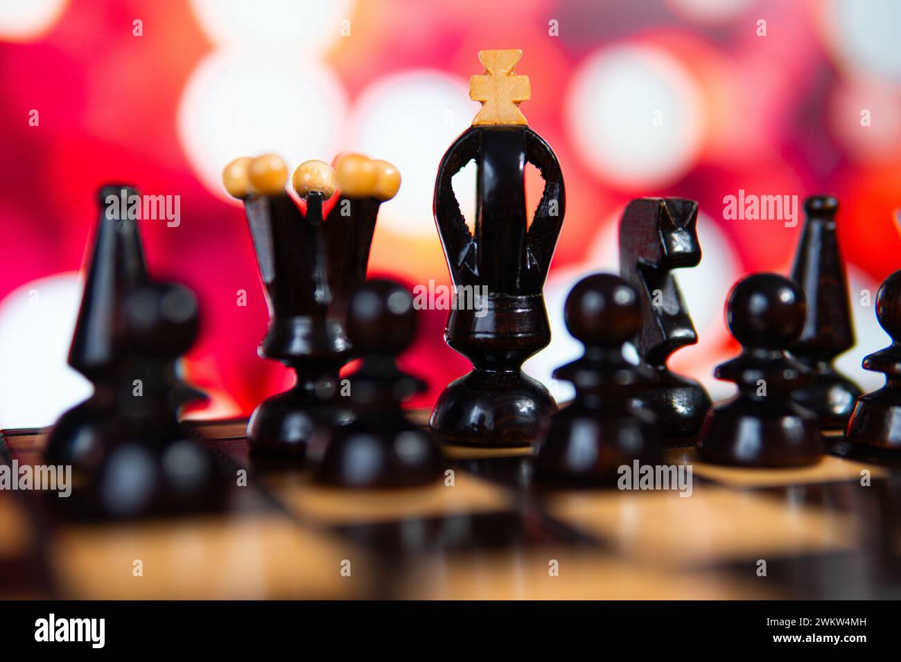 Schwarze Schachfiguren mit Bokeh-Lichtern im Hintergrund. Symbolisiert Strategie und Rivalität. Stockfoto