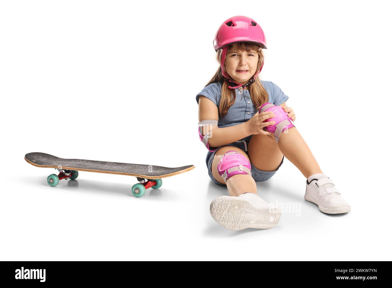 Mädchen, das vom Skateboard fällt und das Knie verletzt, isoliert auf weißem Hintergrund Stockfoto