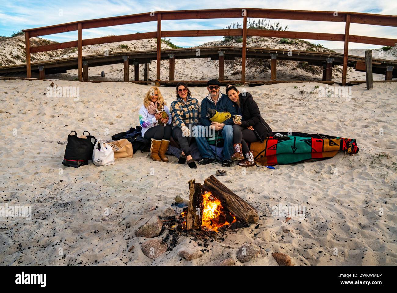 Eine Gruppe von Freunden sitzt auf einem Holzblock in Asilomar Beach, CA, und macht am Weihnachtstag ein Picknick. Stockfoto