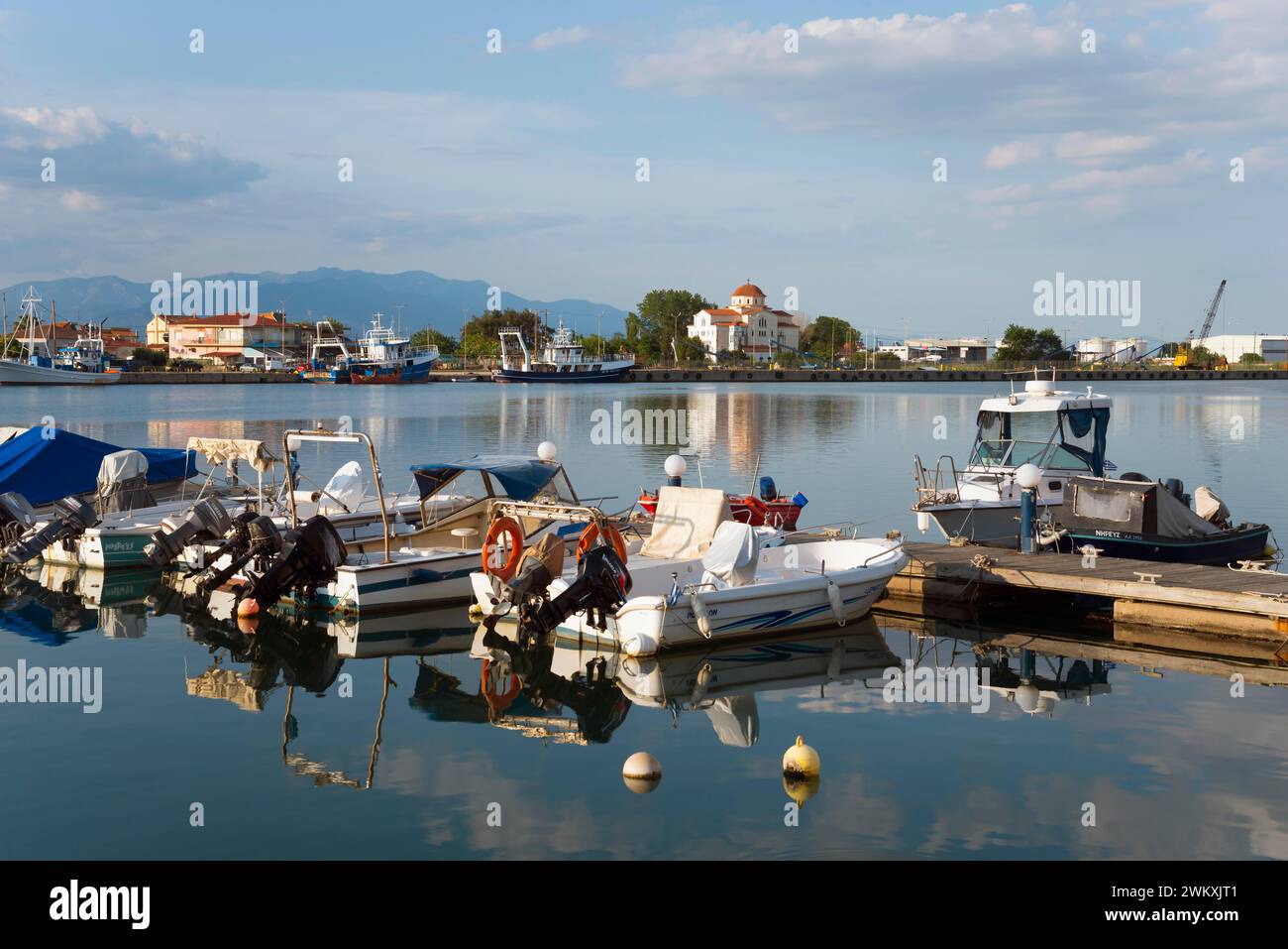 Motorboote liegen an einem kleinen Steg in einem ruhigen Hafen mit einem Bergpanorama im Hintergrund, Hafen und Blick auf Porto Lagos, Xanthi Stockfoto