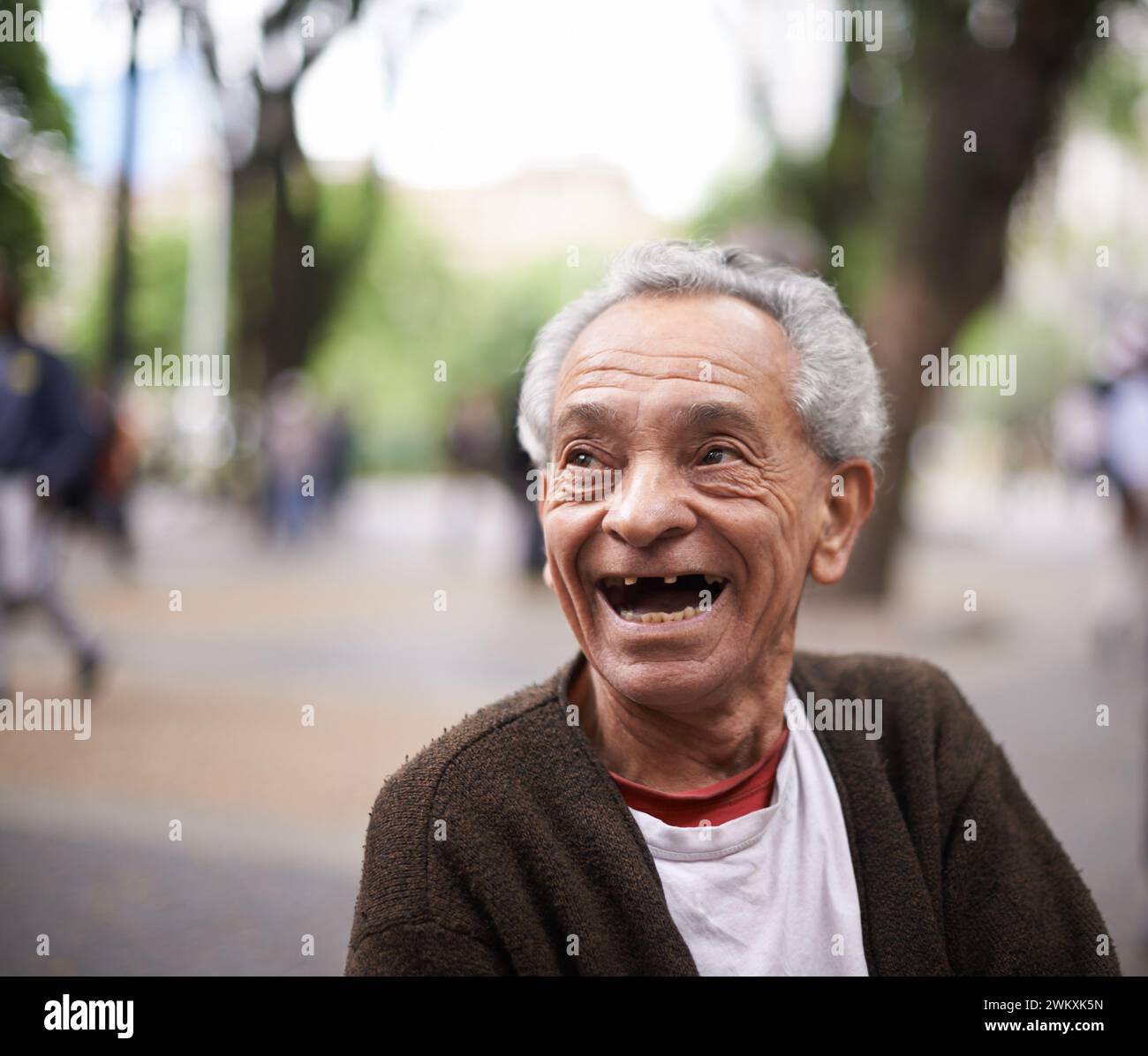 Alter Mann, lacht und ruht im Park für Ruhestand, Glück und gute Laune in Südafrika. Fröhlich, Rentner und Lächeln für albern, albern oder lustig Stockfoto