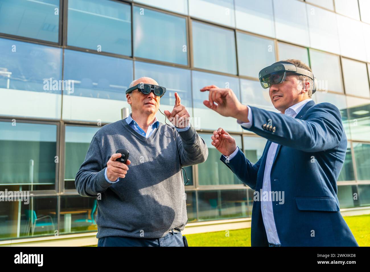 Ein alter Geschäftsmann mit einem Kollegen im Virtual-Reality-Simulator-Gesten im Finanzdistrikt Stockfoto