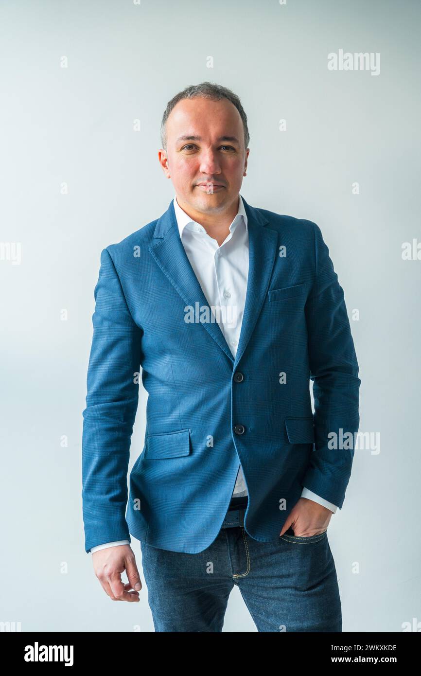 Vertikales Studio-Porträt mit grauem Hintergrund eines Geschäftsmannes in lässiger, eleganter Kleidung stehend Stockfoto