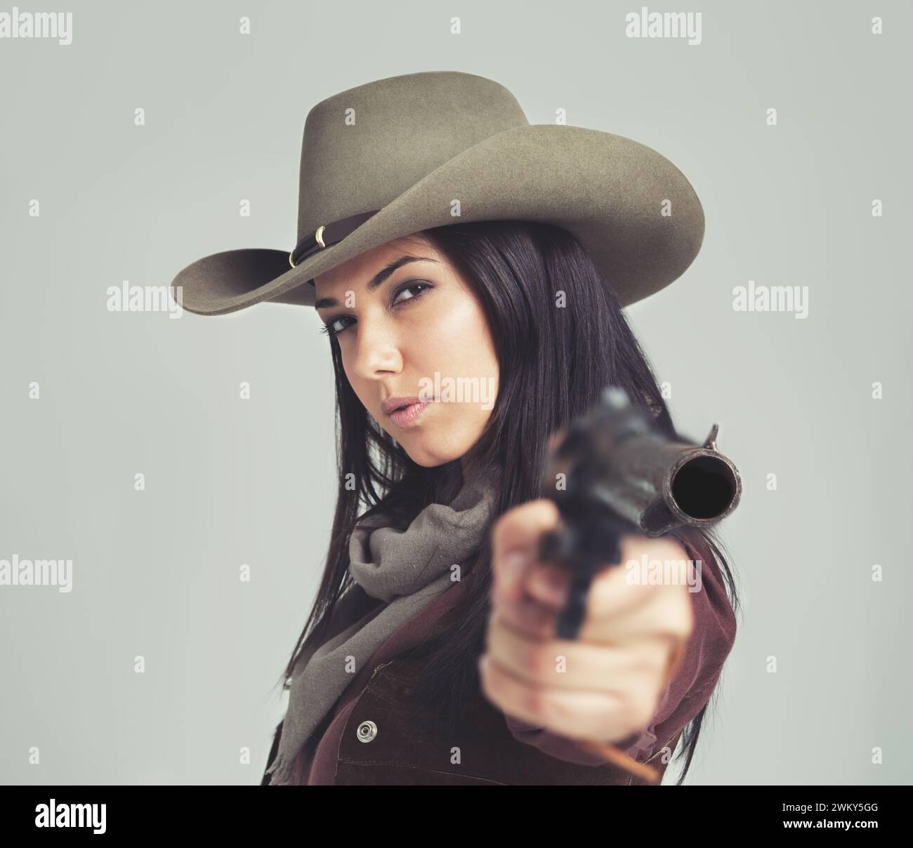 Frau, Cowgirl und Porträt oder Zeigewaffe für wilde Westernkostüme auf weißem Hintergrund, Rodeo oder Outfit. Weibliche Person, Revolver und Cowboyhut Stockfoto