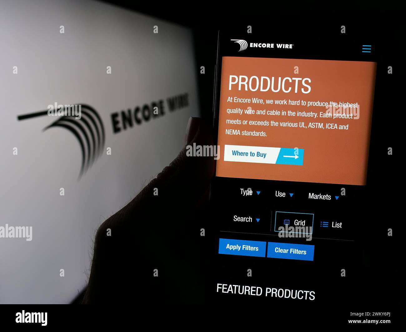 Person, die ein Smartphone mit einer Webseite des US-Kabelherstellers Encore Wire Corporation mit Logo hält. Konzentrieren Sie sich auf die Mitte des Telefondisplays. Stockfoto