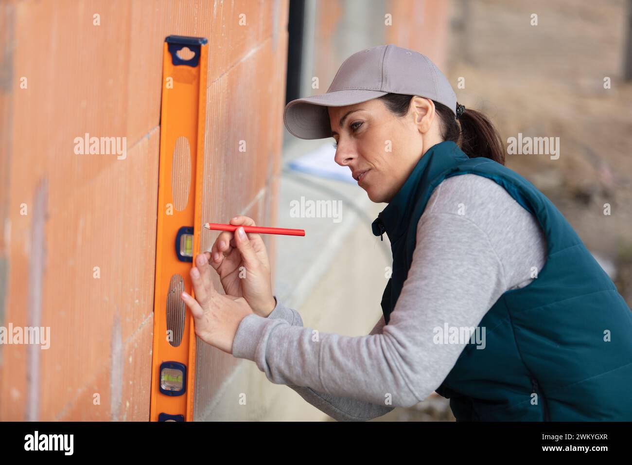 Weibliche Bauarbeiterin mit vertikaler Wasserwaage Stockfoto
