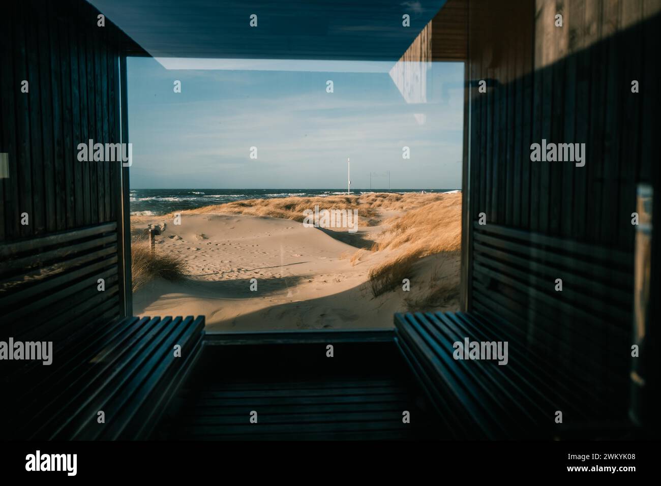 Ein großes Fenster, dahinter die Dünen, die Sonne und die Ostsee Stockfoto