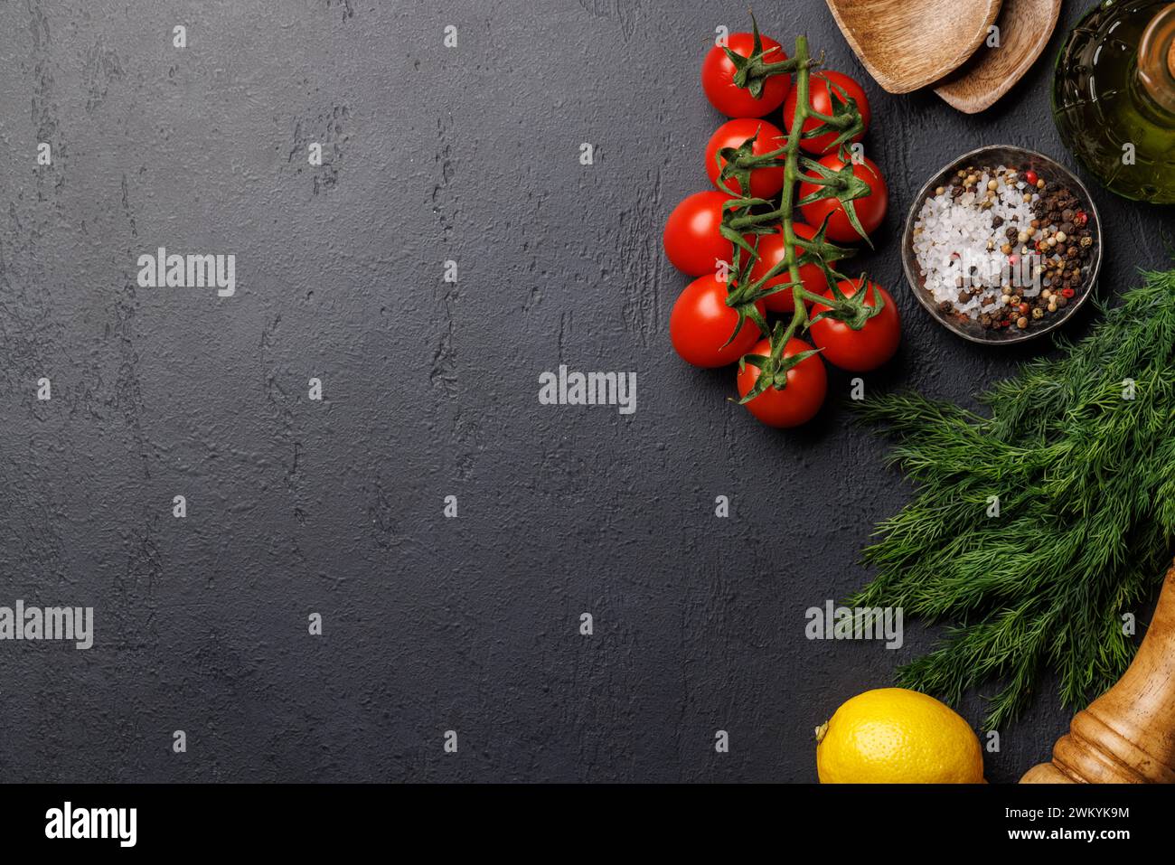 Kochszene: Kirschtomaten, Kräuter und Gewürze auf dem Tisch. Flache Ladefläche mit Kopierraum Stockfoto